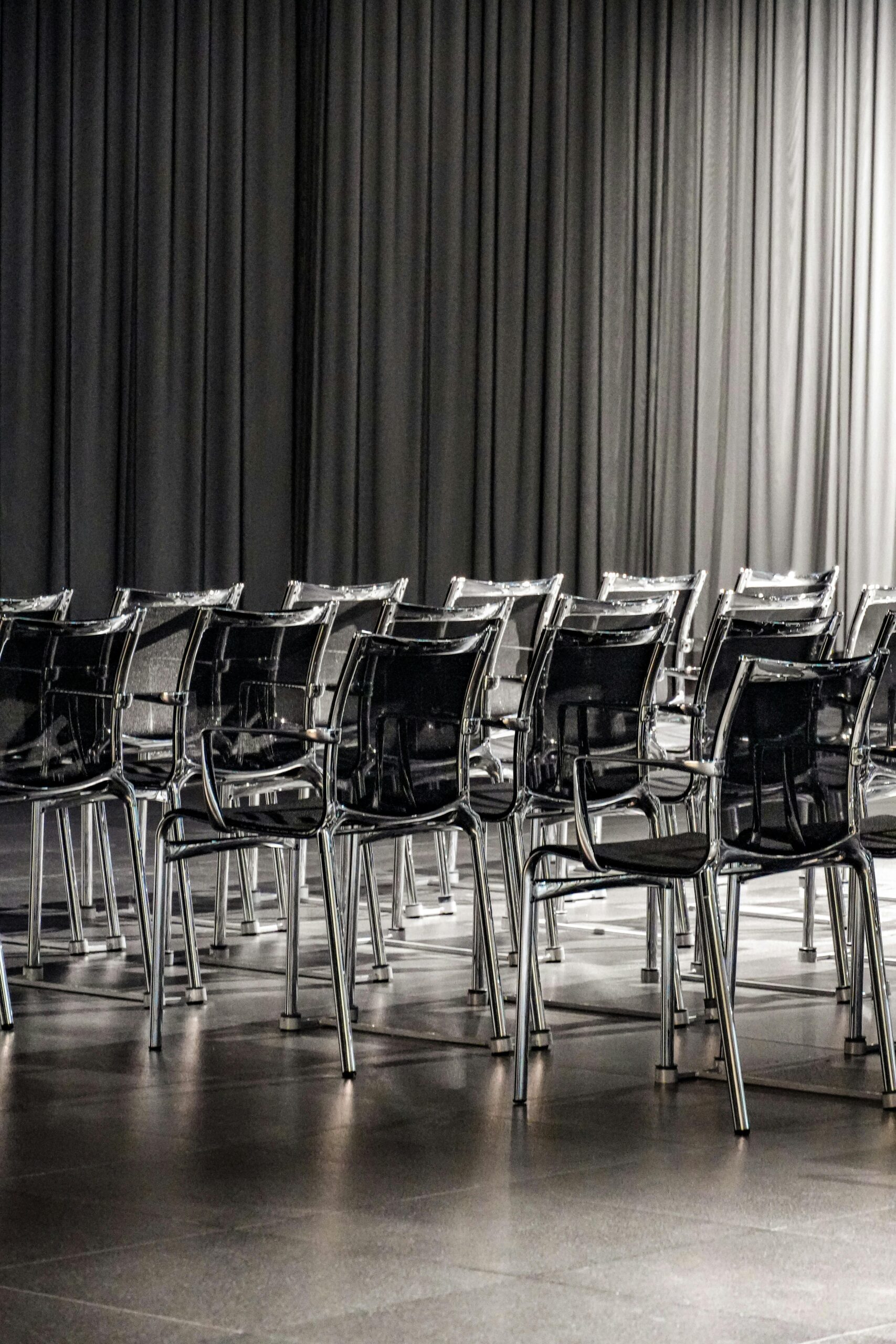 Rows of empty transparent chairs in a modern conference room, creating a minimalist aesthetic.